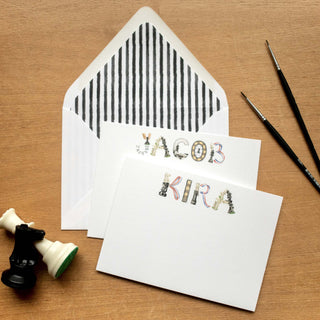 Chess Personalized Stationery in names "Jacob" and "Kira" spelled in chess letters with black and white stripe envelope liner styled in a flatlay photo with chess pieces