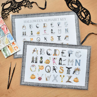 Styled flatlay photo of The Letter Nest Halloween Alphabet Placemat, educational placemat for the kids table featuring Halloween letters painted and printed watercolor A to Z