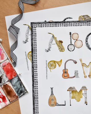 The Letter Nest Musical Instruments Alphabet Print in Flat lay featuring watercolor letters in shapes of musical instruments 