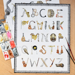 The Letter Nest's Musical Instruments Alphabet styled in flatlay with watercolor paints and brushes