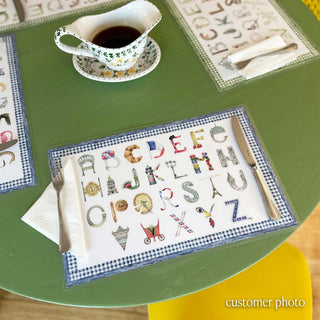 Paris Alphabet Placemat with Blue border styled on a green dining table with flatware settings 