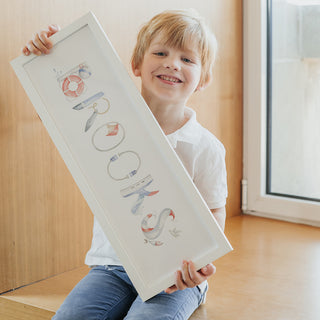 Brooks holds his custom Nautical Name Print in a white frame
